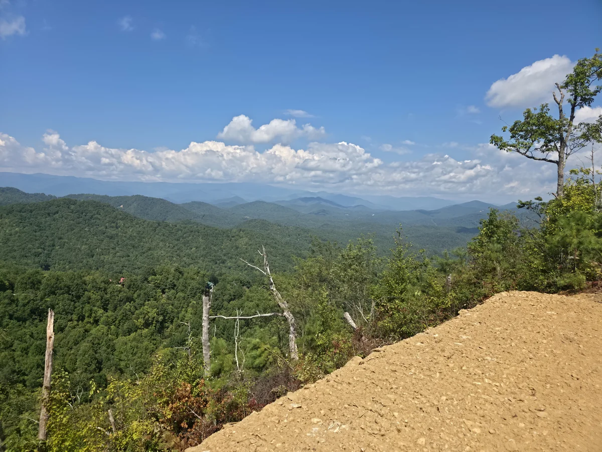 Forested ridges and mountain skyline beyond the clearing edge at the Lot 12 photo stop
