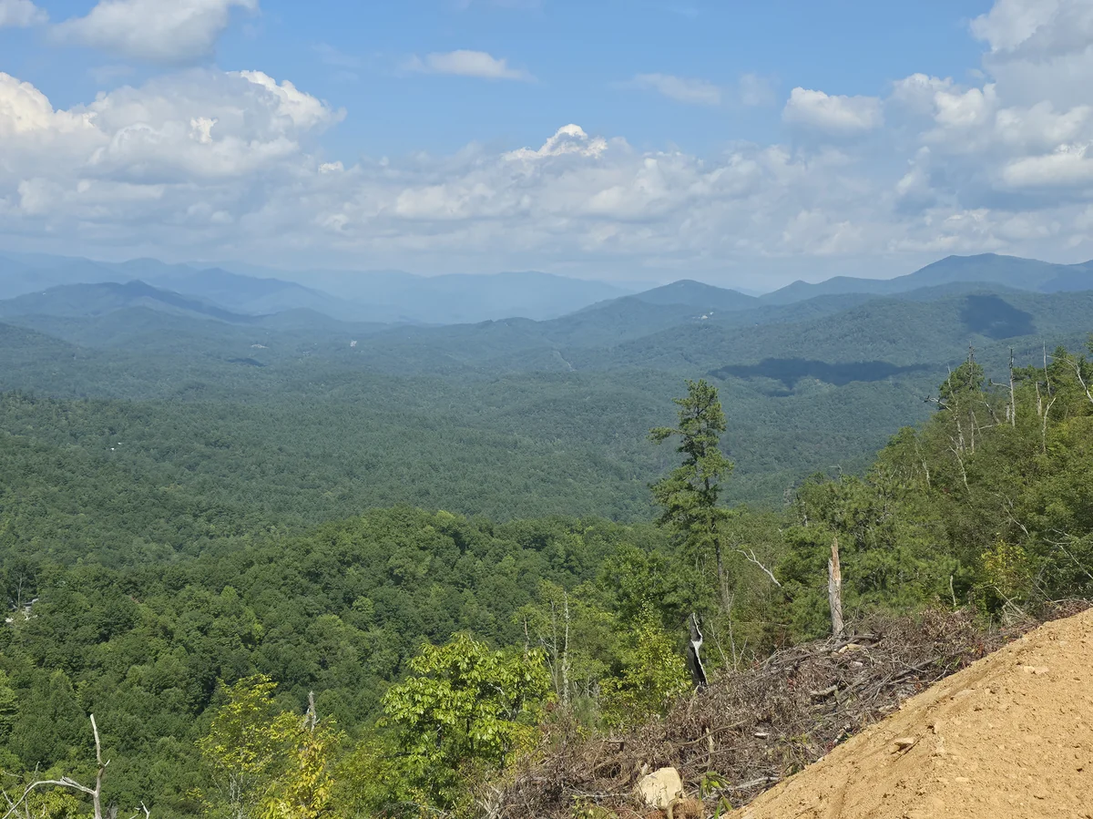 Forested valley and layered ridges beyond the clearing edge in the supplied Lot 9 photograph